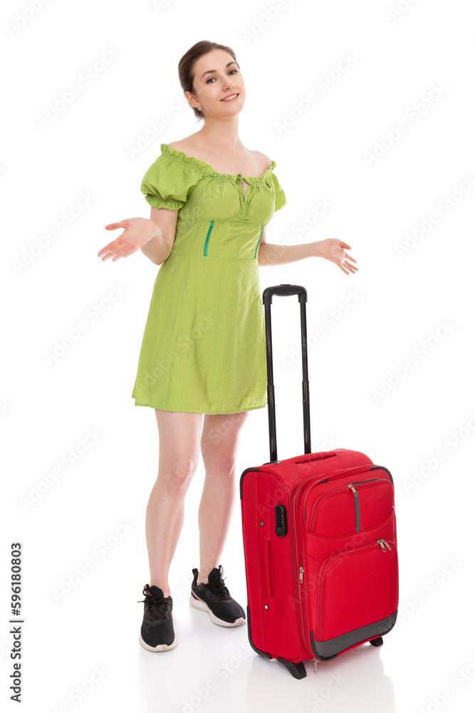 Full length portrait of perplexed girl in green dress with red suitcase to travel, isolated on white background. Young woman waiting for transport and spreads her arms to the sides, posing in studio. Full length portrait of perplexed girl in green dress with red suitcase to travel, isolated on white background. Young woman waiting for transport and spreads her arms to the sides, posing in studio.