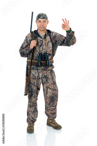 Full lengt portrait of serious duck hunter with a rifle and binoculars show ok okay gesture, isolated on white background. Fifty-year-old man in hunting uniform standing in studio.
