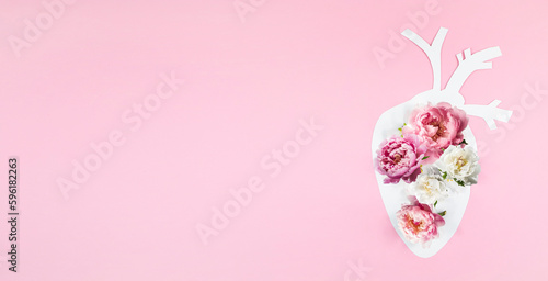 Anatomical paper heart with natural natural flowers on a pink paper background. Therapy, healthcare and treatment concept. Banner, Copy space, top view.