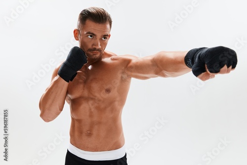 Man athletic bodybuilder poses in boxing gloves with nude torso abs in full-length background, boxing and martial arts. Advertising, sports, active lifestyle, competition, challenge concept. 