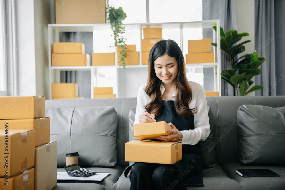 .Young business owner woman prepare parcel box and standing check online orders for deliver to customer on tablet, laptop Shopping Online concept. .Young business owner woman prepare parcel box and standing check online orders for deliver to customer on tablet, laptop Shopping Online concept.
