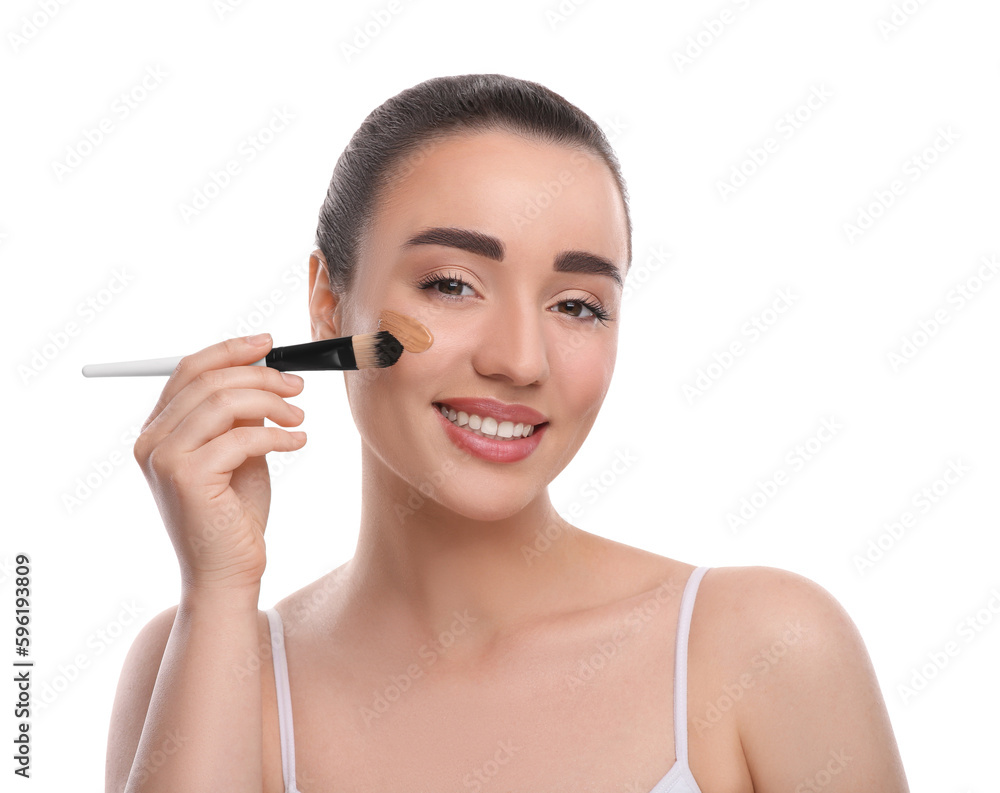 Woman applying foundation on face with brush against white background