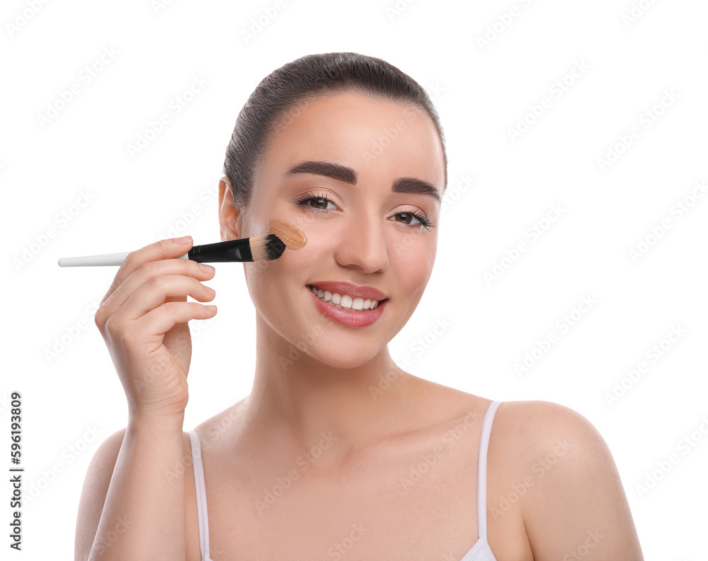 Woman applying foundation on face with brush against white background Woman applying foundation on face with brush against white background