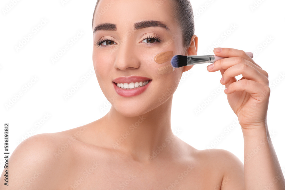 Woman applying foundation on face with brush against white background Woman applying foundation on face with brush against white background