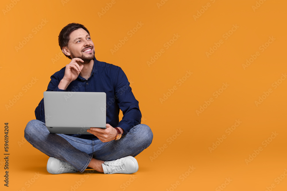 Happy man with laptop sitting on yellow background, space for text Happy man with laptop sitting on yellow background, space for text