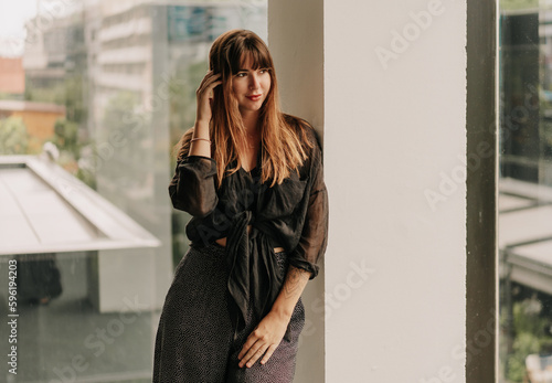 Stylish brunette woman in cashual outfit posing over urban background.