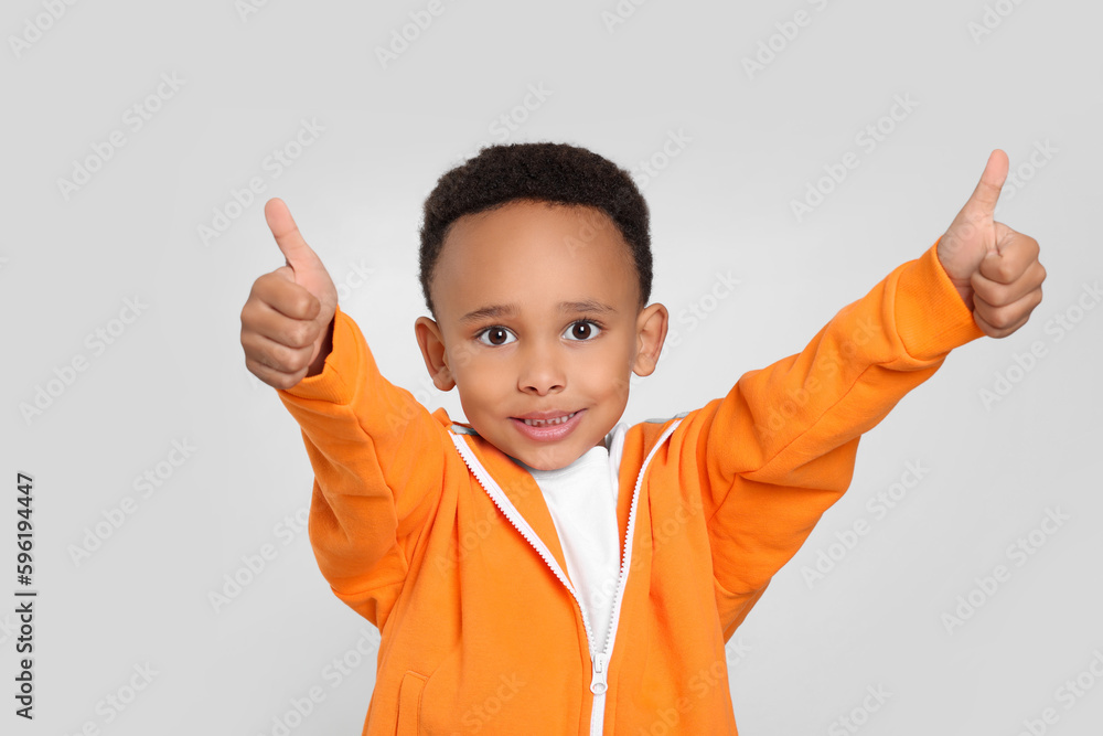 African-American boy showing thumbs up on light grey background African-American boy showing thumbs up on light grey background