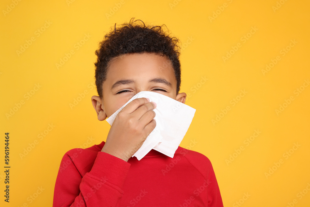 African-American boy blowing nose in tissue on yellow background. Cold symptoms African-American boy blowing nose in tissue on yellow background. Cold symptoms