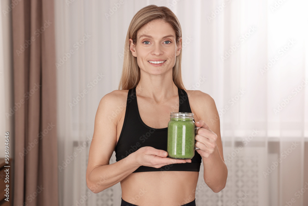Young woman in sportswear with mason jar of fresh smoothie at home Young woman in sportswear with mason jar of fresh smoothie at home