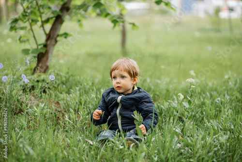 A child walks in nature on a sunny day. Little boy running in the park. Child having fun and enjoy a weather. All kids love play with stick. Happy childhood. A little child boy outside looking far. © elenbessonova