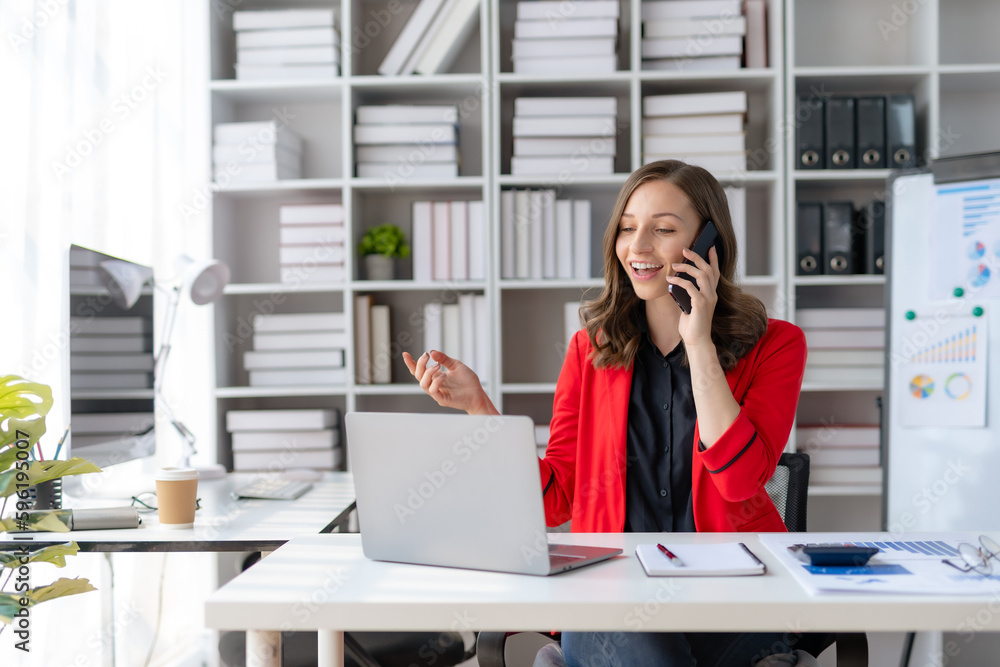 Obraz premium Beautiful smiling businesswoman talking on mobile phone while working in office.