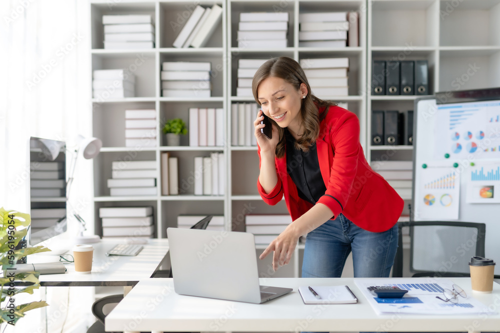 Beautiful smiling businesswoman talking on mobile phone while working in office. Beautiful smiling businesswoman talking on mobile phone while working in office.