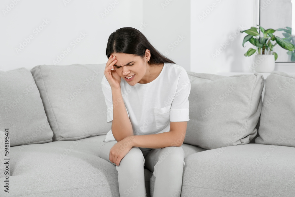 Young woman suffering from headache on sofa at home. Hormonal disorders Young woman suffering from headache on sofa at home. Hormonal disorders