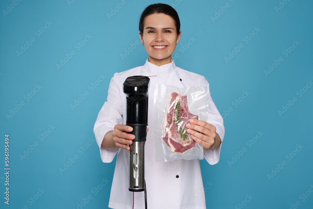 Chef holding sous vide cooker and meat in vacuum pack on light blue background Chef holding sous vide cooker and meat in vacuum pack on light blue background