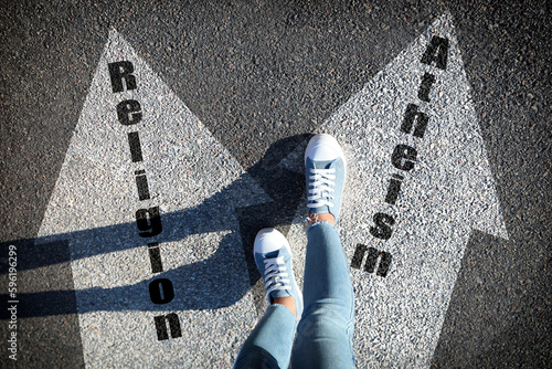 Philosophical or religious position. Woman standing on road marking arrow with word Atheism, closeup