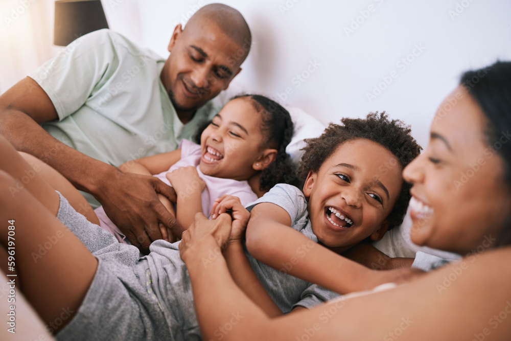 Happy family, relax and playing in bed with smile for free time, weekend or fun holiday morning at home. Mother, father and children relaxing and laughing together for playful joy in the bedroom