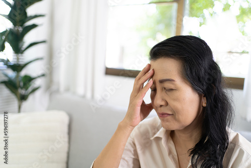 Middle age Asian woman touching forehead having headache suffering from. migraine feeling sick or depression