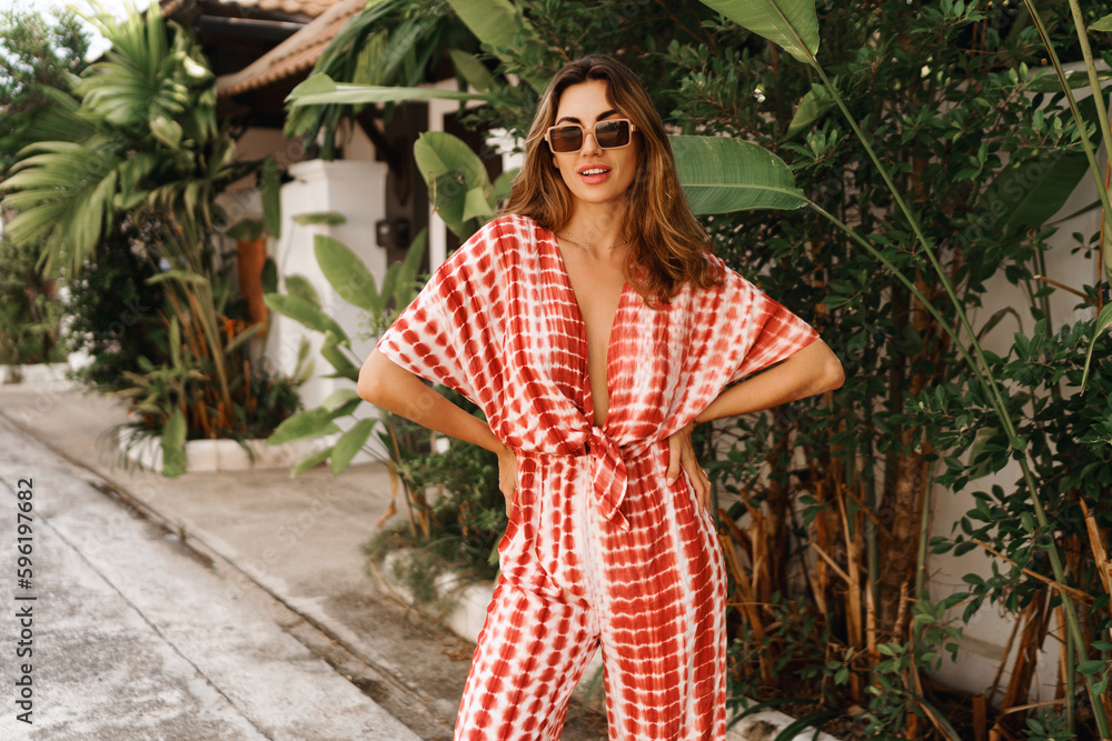 Outdoor fashion portrait of brunette young woman posing near palm trees and wearing modern trendy outfit . tropical vacation mood. Outdoor fashion portrait of brunette young woman posing near palm trees and wearing modern trendy outfit . tropical vacation mood.