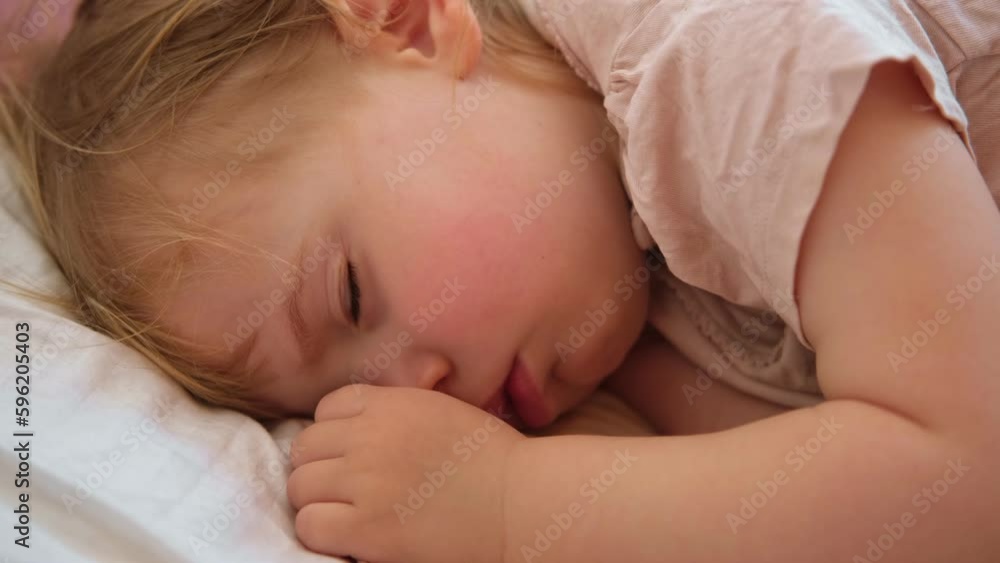 Peaceful adorable baby sleeping on his bed at home. Sleeping newborn baby concept. One year old baby girl sleeps peaceful at domestic room interior background. Serene dream. Cute Face Close Up. Peaceful adorable baby sleeping on his bed at home. Sleeping newborn baby concept. One year old baby girl sleeps peaceful at domestic room interior background. Serene dream. Cute Face Close Up.