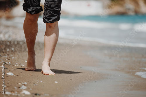 Vacation concept. Close up of female legs walking by the beach © olyphotostories