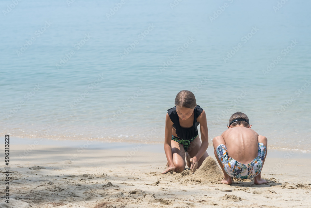 boy and girl building a sand castle on the blue sea