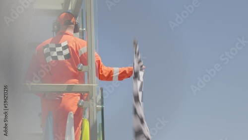 Man holding and waving Checkered race at finish line on a raceway. Victory, achievement, success and sport concept. 
