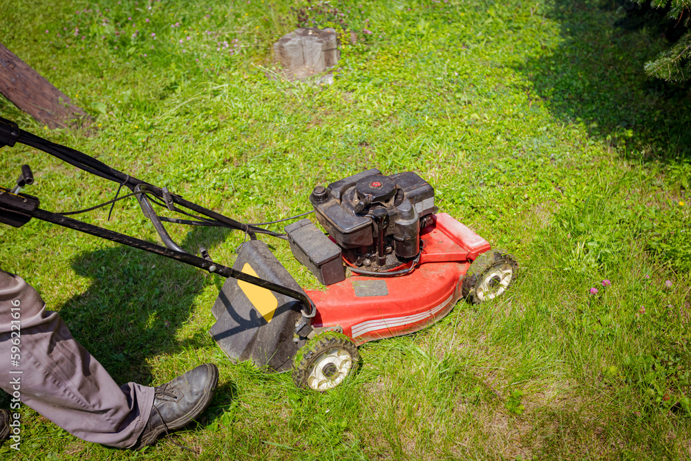 Farmer is mowing lawn in the garden with a petrol lawn mower Farmer is mowing lawn in the garden with a petrol lawn mower