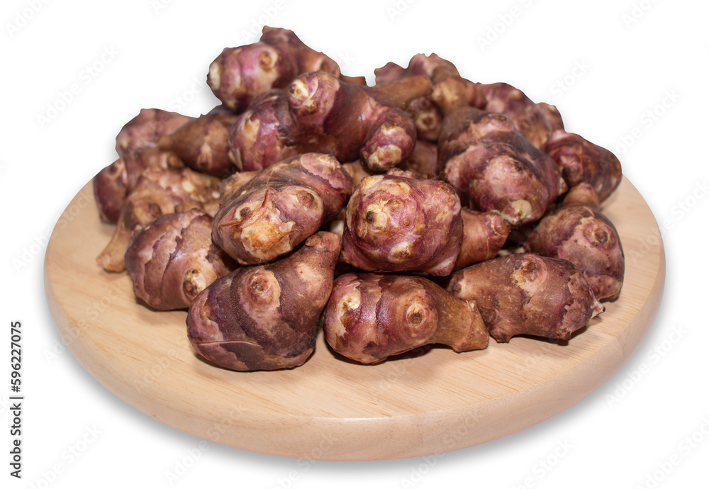 Jerusalem artichoke on a round wooden cutting board isolated on a white background with clipping path. Jerusalem artichoke on a round wooden cutting board isolated on a white background with clipping path.