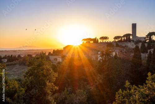 Italy, Lazio, Tarquinia, Trees in front of rural town at sunset photo