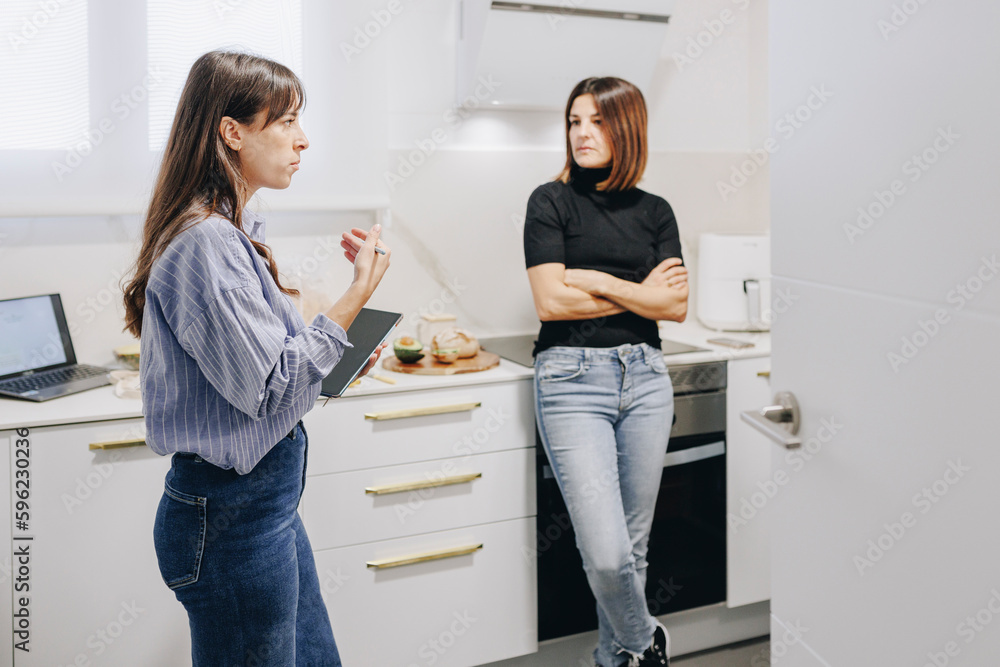 Nutritionist explaining client standing with arms crossed in kitchen at home Nutritionist explaining client standing with arms crossed in kitchen at home
