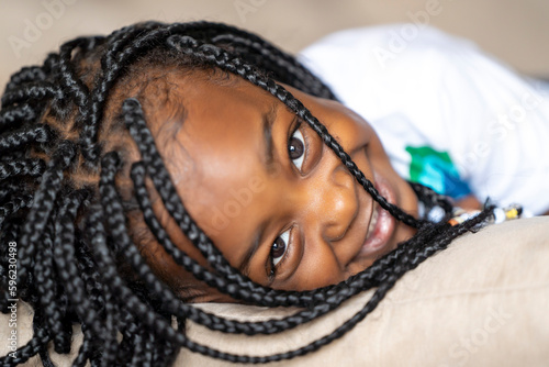 Smiling girl with braided hair lying at home