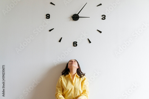 Woman under large clock on wall photo