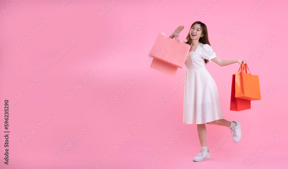 full body image of asian woman holding shopping bag and posing on pink background full body image of asian woman holding shopping bag and posing on pink background
