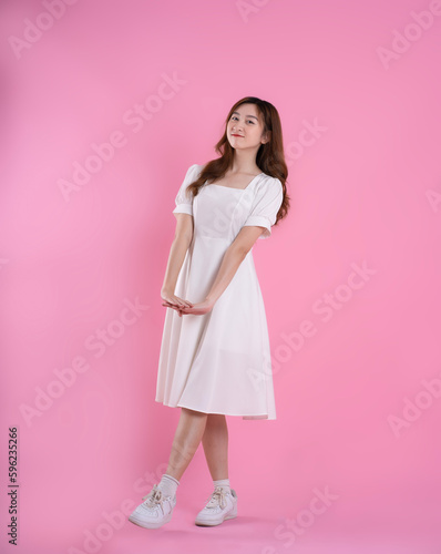 full body image of asian businesswoman using laptop on pink background