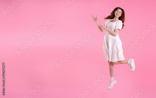 full body image of asian woman in skirt posing on pink background
