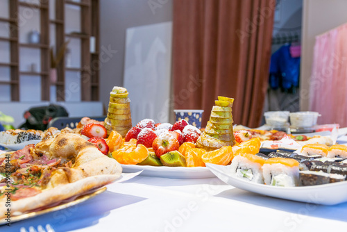 On white banquet table are delicious food plates: fruit salad, pizza, land. Children's birthday.