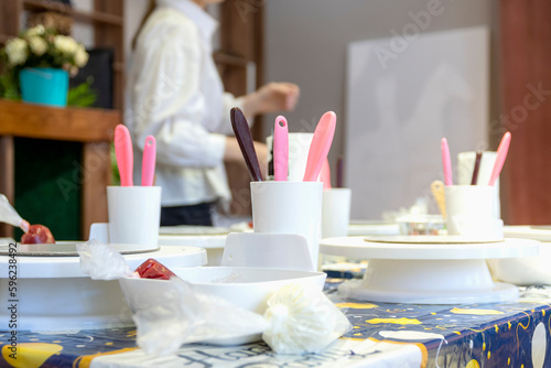 Kitchen belongings and incrades (cream) lie on kitchen table. Master class of culinary business for child.
