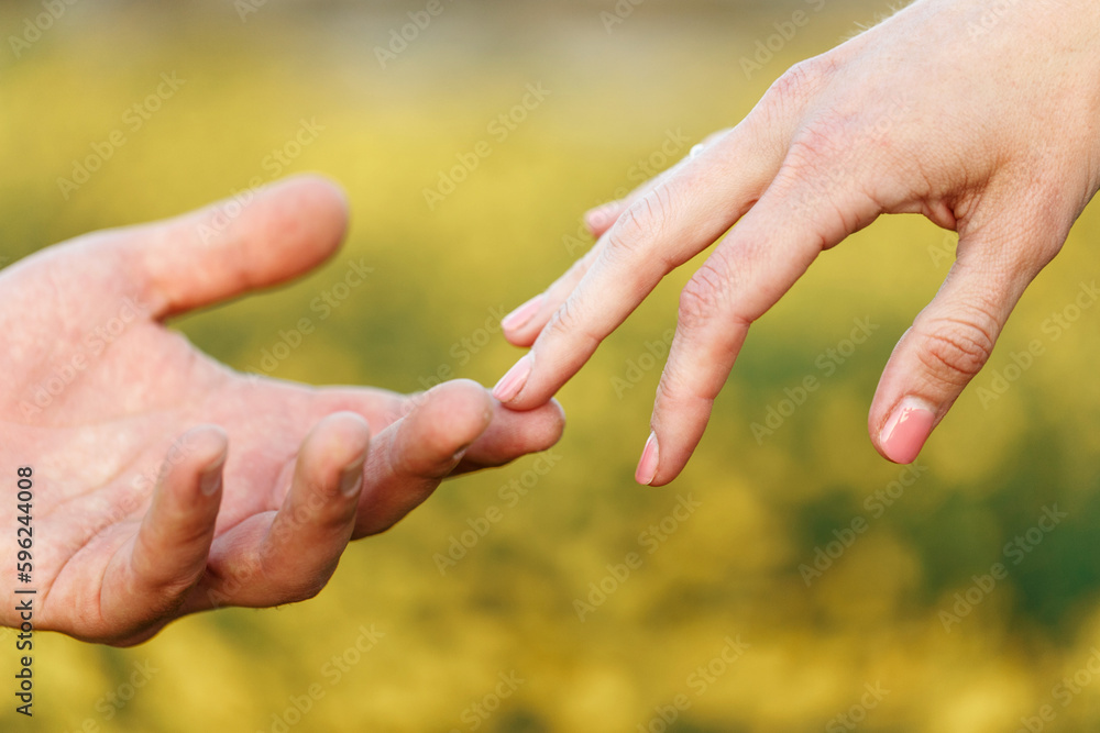 Male and female hands reaching out to each other copying creation of Adam sign. Natural sunset light Male and female hands reaching out to each other copying creation of Adam sign. Natural sunset light