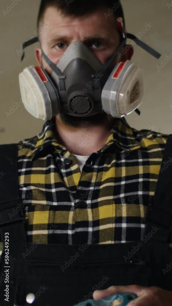 a man of European appearance in protective mask with a woodworking tool in his hands looks at the camera, working in a carpentry workshop a man of European appearance in protective mask with a woodworking tool in his hands looks at the camera, working in a carpentry workshop