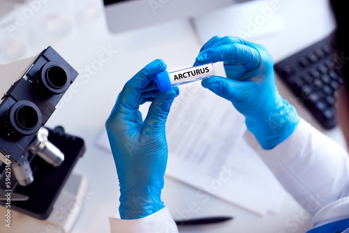 Close Up Of Lab Worker Conducting Research Using Microscope Holding Test Tube With Arcturus photo