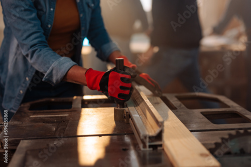 Close up on woman using table saw.