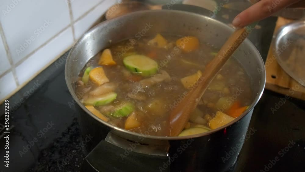 View of a vegetable soup being stirred in a steaming pot in slow motion 4K View of a vegetable soup being stirred in a steaming pot in slow motion 4K
