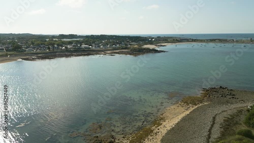 sweeping drone footage of Guernsey coastline, stunning golden beach and clear calm sea with boats at anchor on sunny summer day .Cottages and Peninsula Hotel in the background. photo