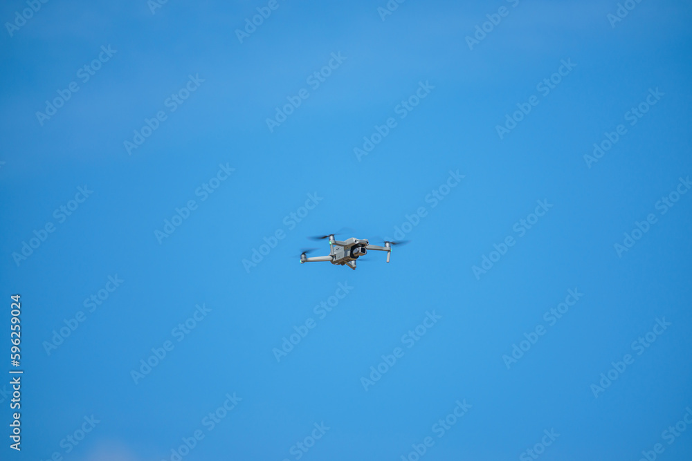 a drone with a high-resolution digital camera flies against a blue sky with clouds, a drone hovers in the air against the sky, a copter hovers in the air