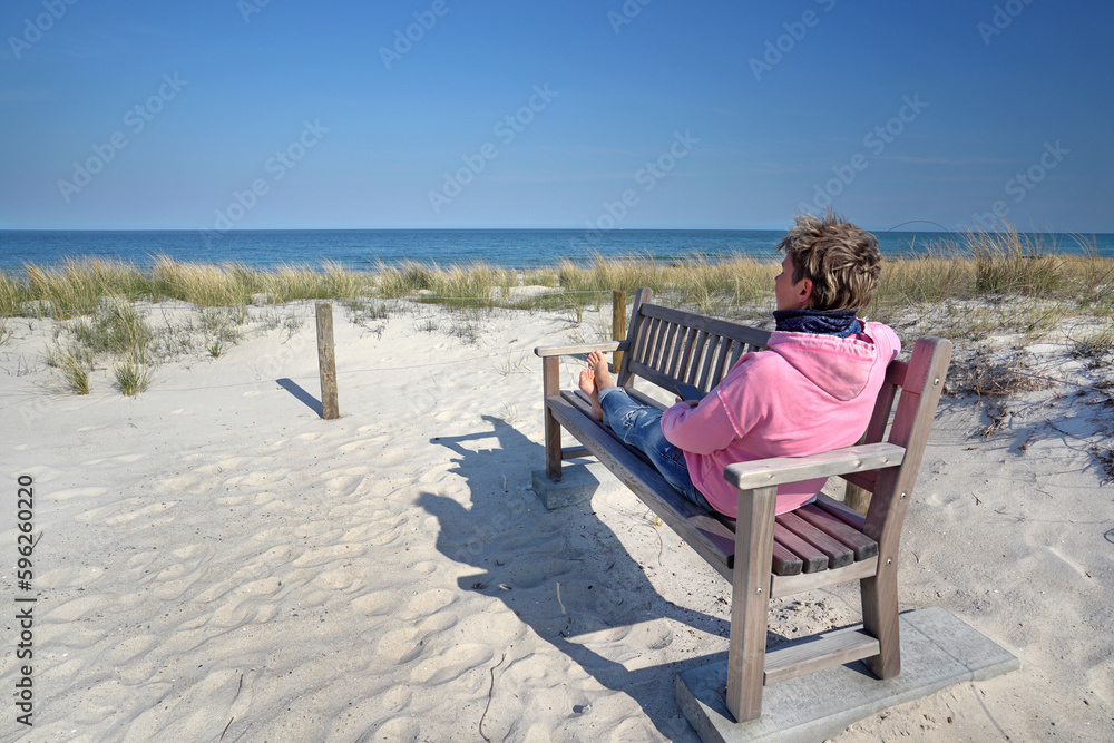 Frau sitzt auf einer bank am Strand 