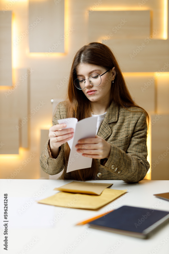 A young businesswoman holds financial reports and business mail in her hands. A young businesswoman holds financial reports and business mail in her hands.