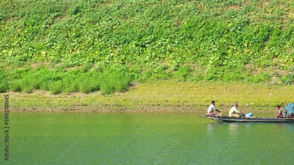 Bengali Fishermen and Villagers Rowing a Long Pirogue along a Slowly Flowing River in front of a Vividly Vegetalised Riverbank, Bangladesh (UHD) Bengali Fishermen and Villagers Rowing a Long Pirogue along a Slowly Flowing River in front of a Vividly Vegetalised Riverbank, Bangladesh (UHD)