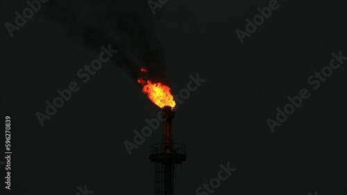 Medium shot, Flames and dark smoke from an industrial tower at night. photo