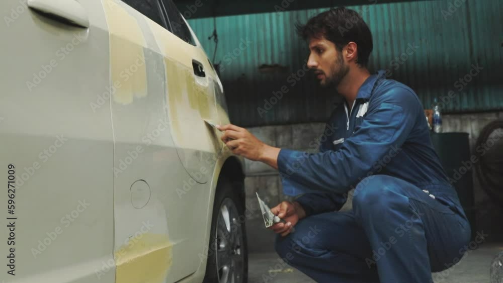 Skilled male car mechanic uses trowel and putty to reinforce smooth, clean surface as a paint job in preparation for smoothing and before repainting : Auto mechanic car accident in modern garage. Skilled male car mechanic uses trowel and putty to reinforce smooth, clean surface as a paint job in preparation for smoothing and before repainting : Auto mechanic car accident in modern garage.