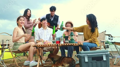 Male and female friends gang sitting and drinking beer having fun on vacation traveling camping traveling holiday enjoying the natural field.